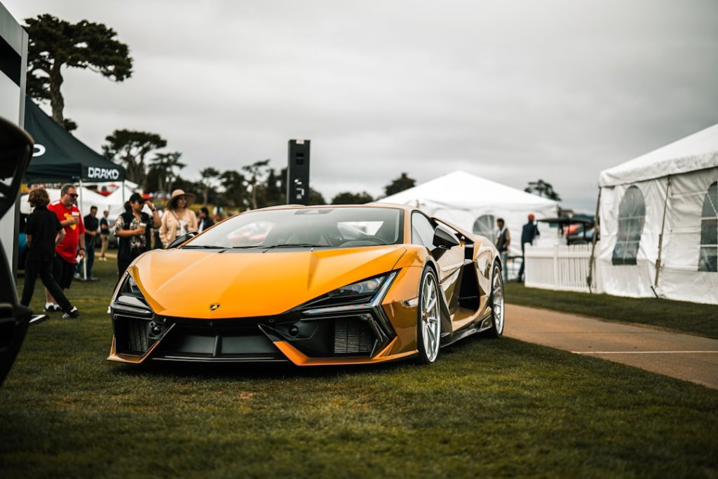 Orange sports car on display at an outdoor event.
